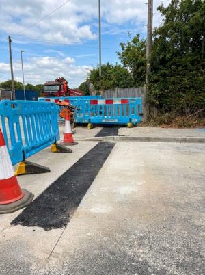 Freshly resurfaced trench running across concrete pavement, bordered by blue barriers and cones, at the Anstey Lane electrical trenching and joint bay site