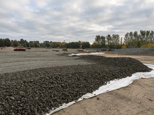 Layers of gravel and soil being spread across the Copart Dunfermline site by construction machinery during ground preparation