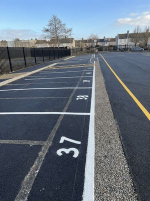 Completed surface car park in Stratford with freshly painted parking bays, clear markings, and perimeter fencing ready for use