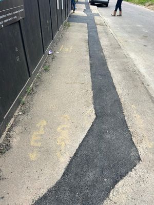 Long completed tarmac reinstatement strip tracing the new LV cable route along Aycliffe Road, Borehamwood, alongside yellow utility markings