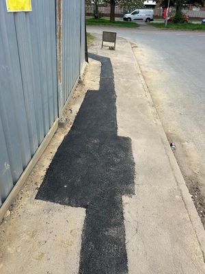 Completed tarmac patch reinstatement against the corrugated steel site hoarding at the Aycliffe Road, Borehamwood LV connection