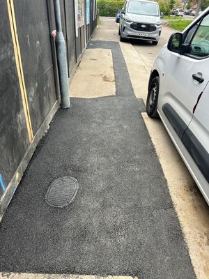 Completed footway tarmac reinstatement around a recessed manhole cover on Aycliffe Road, Borehamwood, after LV cable installation