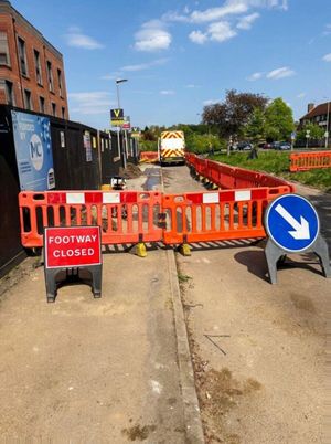 Orange portable barriers and a Footway Closed sign protecting the LV cable installation along the Aycliffe Road footpath in Borehamwood