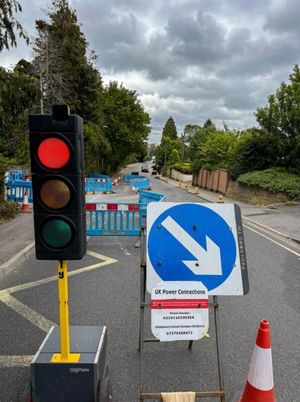 Temporary two way traffic signal and diversion sign on Anstey Lane, Alton, with blue safety barriers and traffic cones during the LV electricity network installation