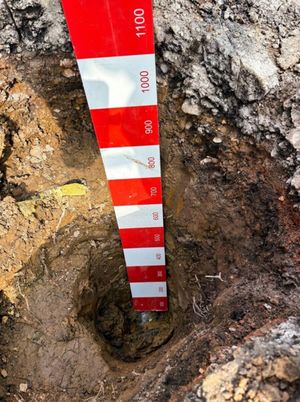 Red and white measuring rod standing in a deep cable trench excavation on Aycliffe Road, Borehamwood, during LV electricity network installation